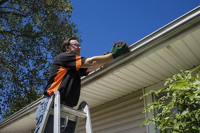 a roofer repairing a damaged gutter on a house in San Mateo